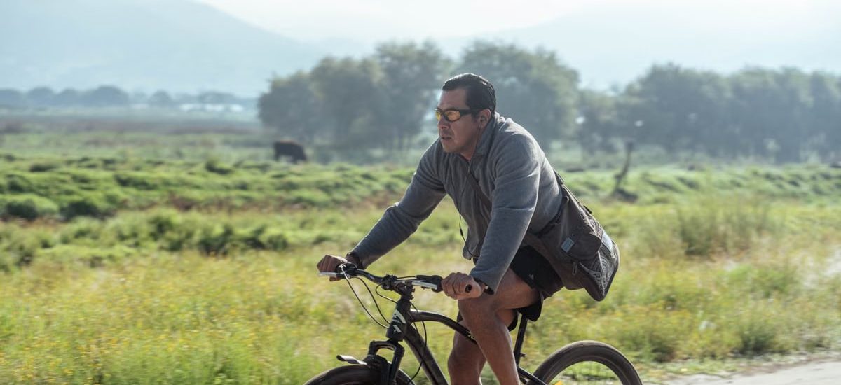 Adult man cycling on a rural path in a natural landscape, wearing casual attire.